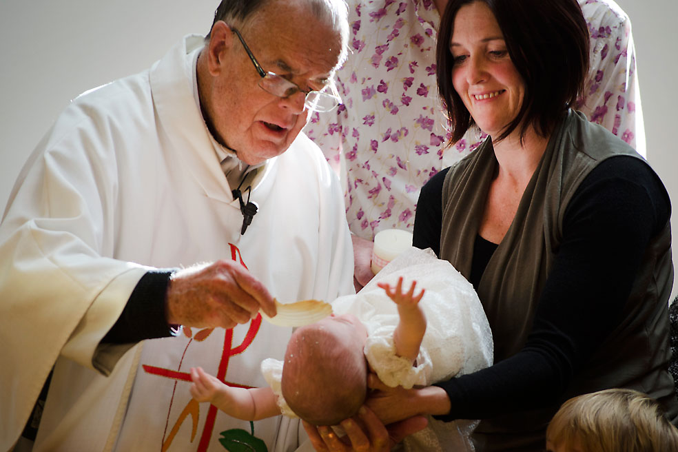 Mgr Tim Hannigan moments before he died, baptising Maisie whom mother Catherine Hollands is holding.