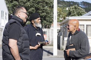 Whānau with photos of their loved ones meet outside the whare.