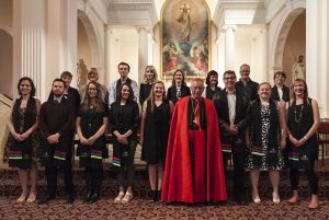 Group of TCI 2016 graduating students with Cardinal John. From left, back: Fiona Rammell, Deborah Matheson, Maurice Atkinson, Emma Dodsworth, Michelle Teahan, Raewyn Sullivan-Brown, Sean Ryan, Christine McDonald. From left, front: Hannah Gilmour, Reuben Fletcher, Roseanne Fletcher, Kathleen Scott-Mead, Eliana King, (Cardinal John Dew), Michael Draper, Katherine Sprowson, Ariana Kooge.